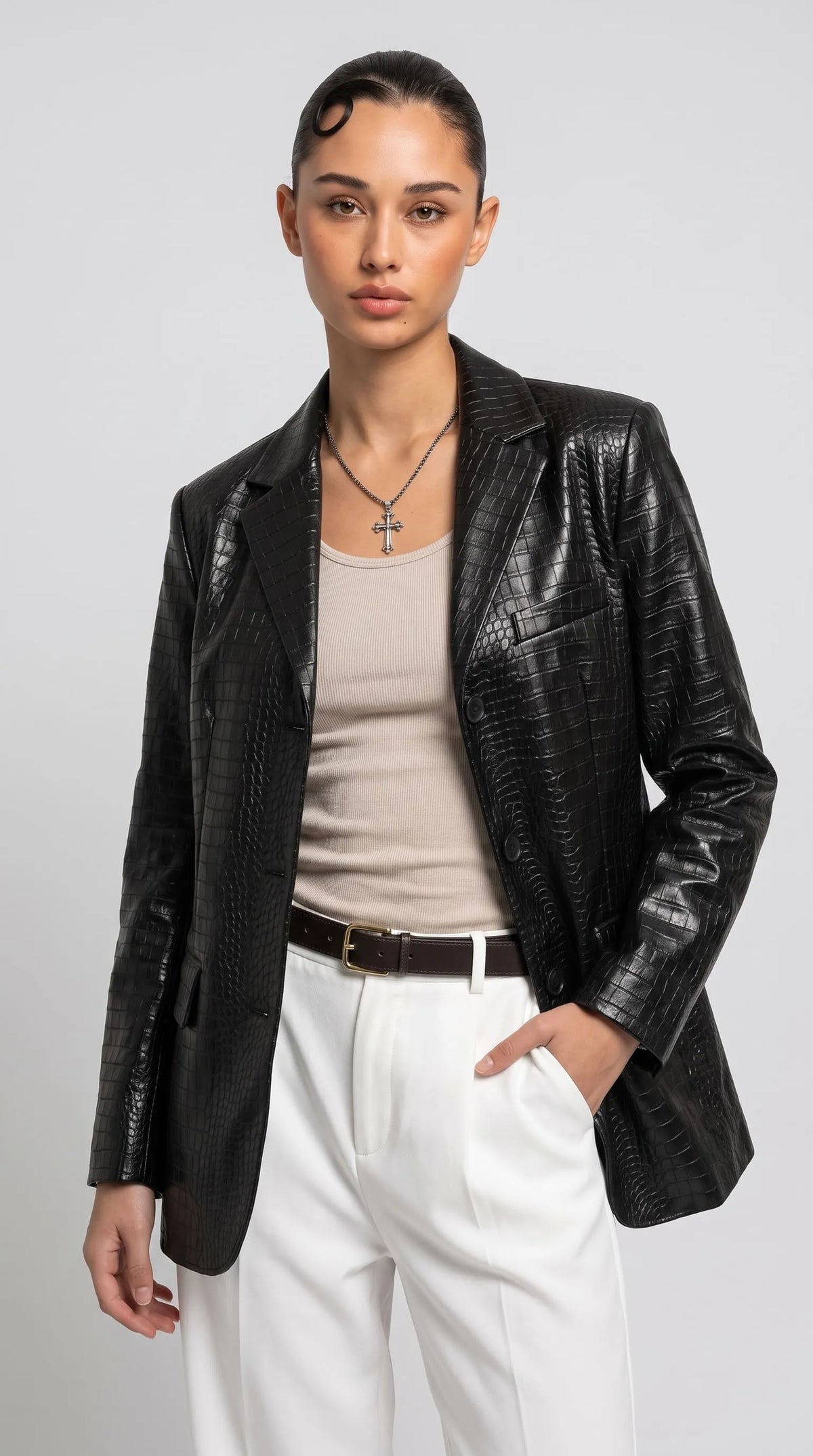 Women's black crocodile-embossed genuine leather blazer styled with a fitted beige top and crisp white tailored trousers for a sophisticated modern outfit. The glossy scaled texture, structured shoulders, classic notch lapels and dark button closure create a confident luxury aesthetic, perfect for elevated city dressing, smart-casual occasions and statement evening fashion.