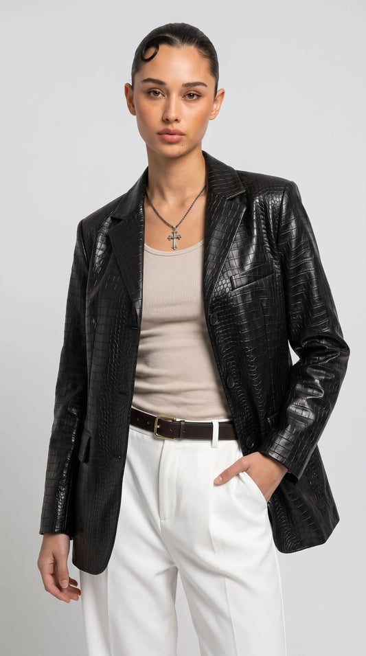 Women's black crocodile-embossed genuine leather blazer styled with a fitted beige top and crisp white tailored trousers for a sophisticated modern outfit. The glossy scaled texture, structured shoulders, classic notch lapels and dark button closure create a confident luxury aesthetic, perfect for elevated city dressing, smart-casual occasions and statement evening fashion.
