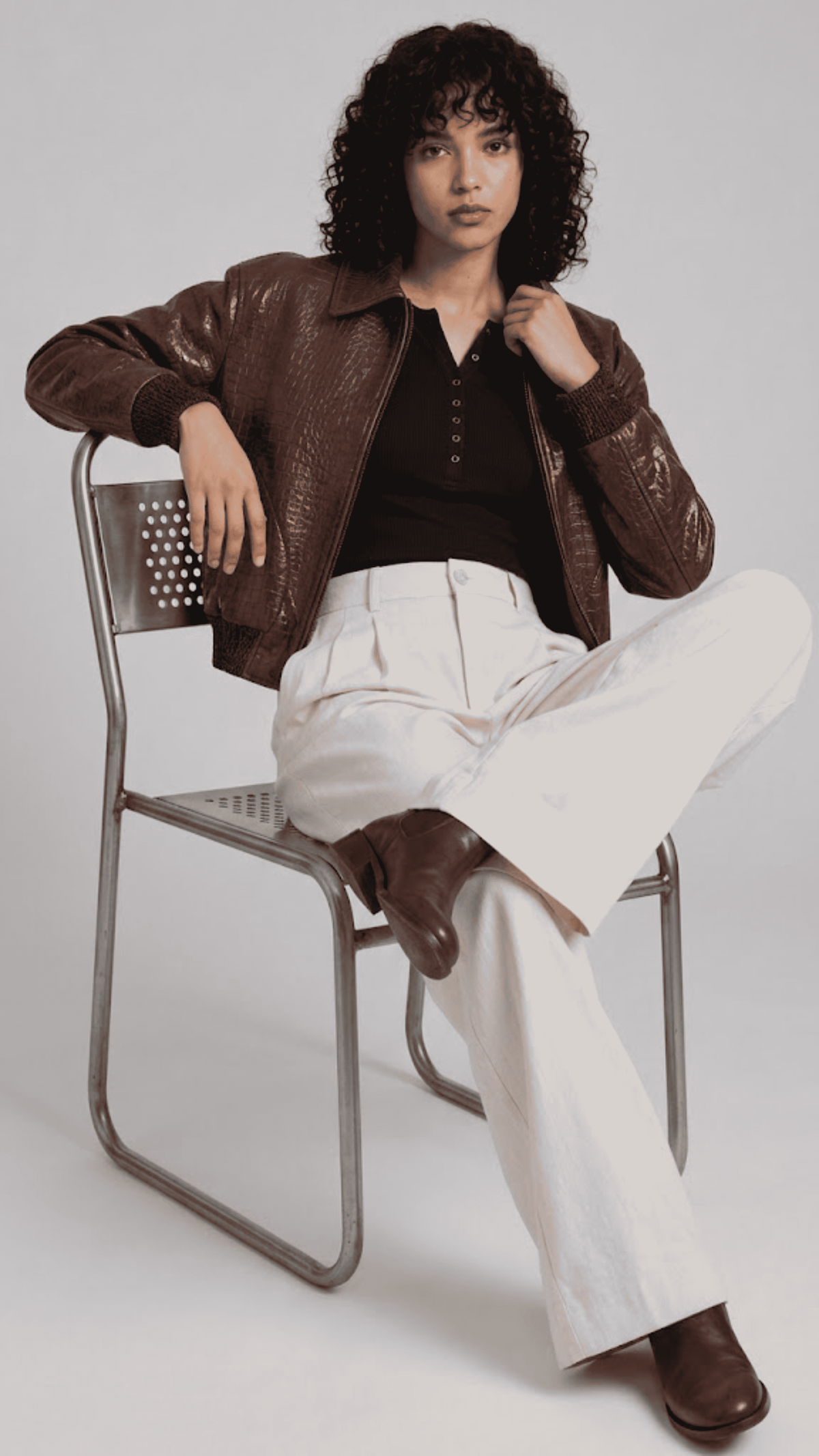 Full-body studio catalog shot of a women's crocodile-print brown leather bomber jacket on a grey backdrop.